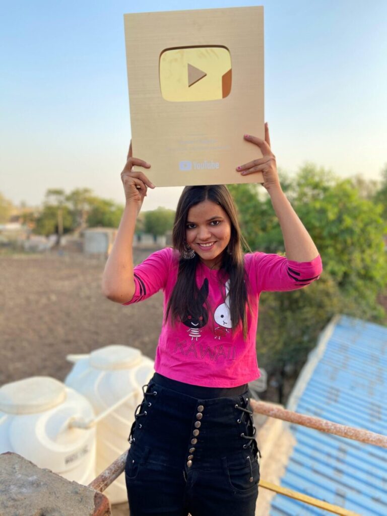 Smiling woman holding a YouTube plaque outdoors in Umri, Madhya Pradesh.