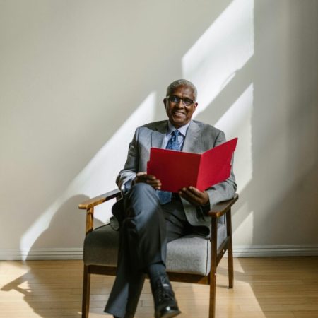 Elderly businessman sitting with a folder in bright office.